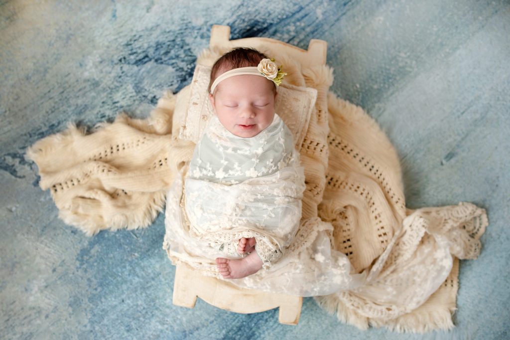 Newborn baby girl in lace and boho fringe layers ontop of a watercolor backdrop and in a trench bowl.