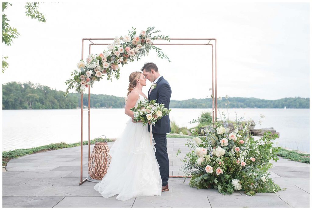 modern chic bride and groom bridal portrait at ceremony space with asymmetrical florals on and around arch at new jersey venue